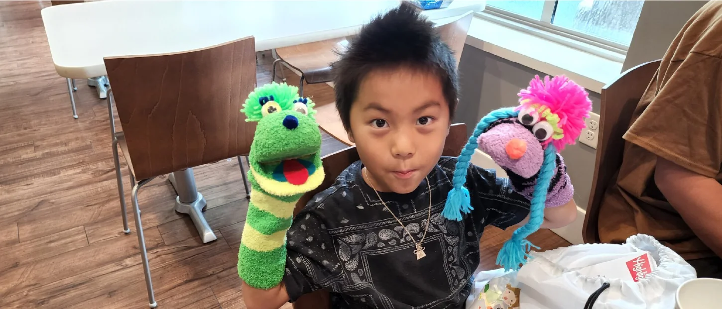 adolescent boy with two puppets on his arms