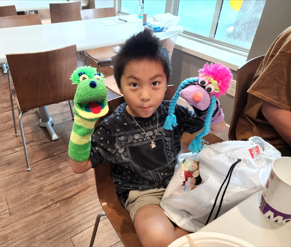 adolescent boy with two puppets on his arms