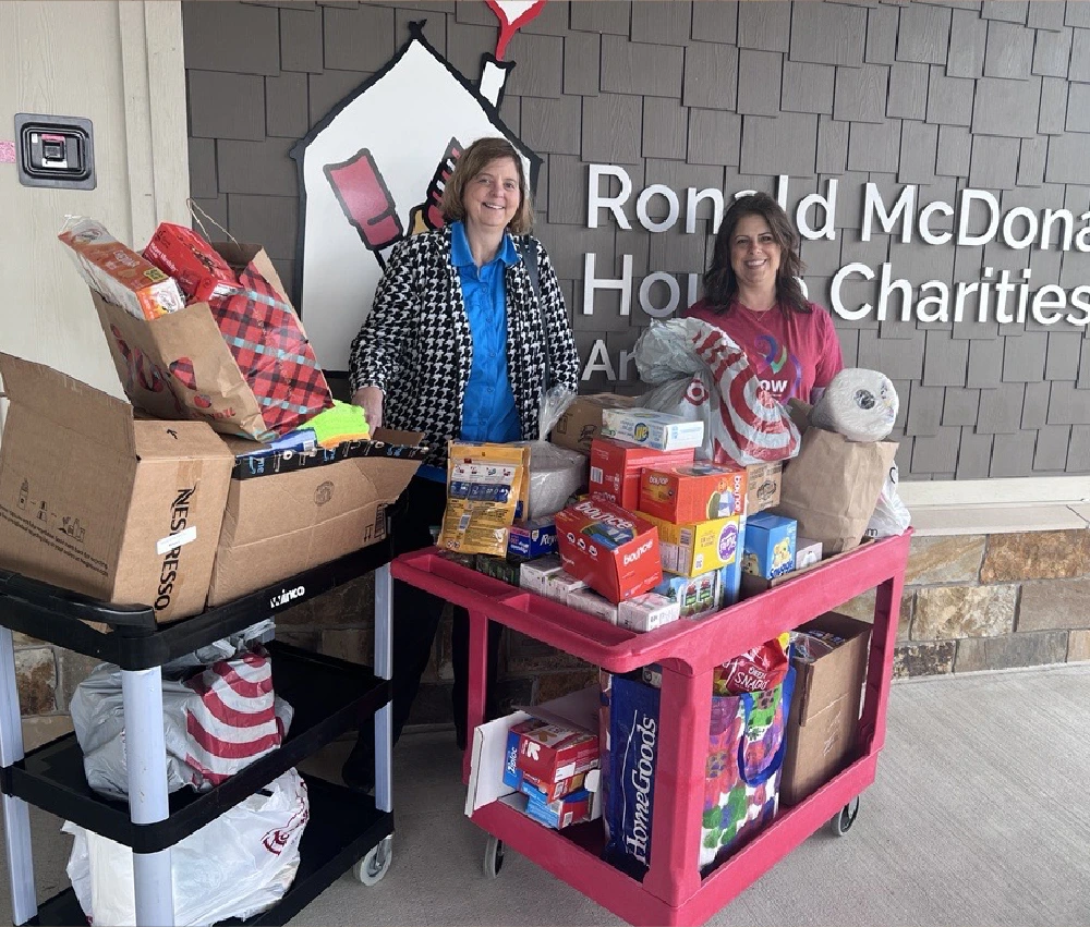 two generous donors standing with two carts full of donated goods