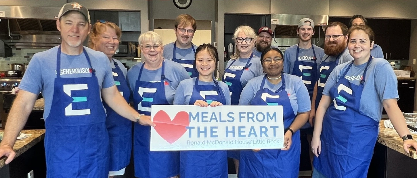 group of volunteers gathered in kitchen all wearing matching aprons for meals from the heart program